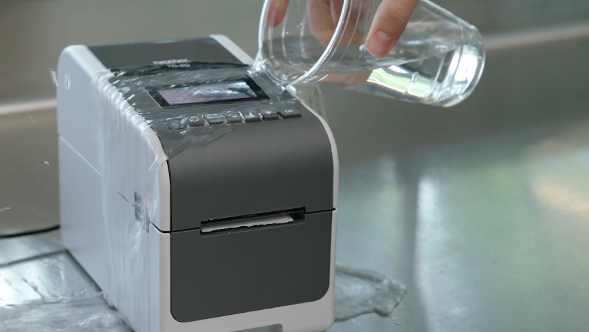 A cup of water is poured onto the printer.